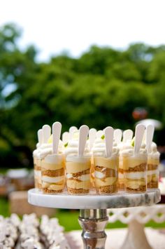 small desserts are arranged on a white cake platter with toothpicks sticking out of them