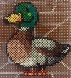 a cross stitch duck on a tile background