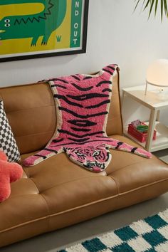 a living room with a brown leather couch and colorful pillows on the top of it