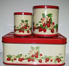 three red and white canisters sitting on top of each other with cherries painted on them