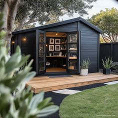 a small backyard shed with its doors open on the deck and potted plants outside