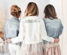 three bridesmaids wearing denim jackets with the word bride printed on them, standing in front of a mirror