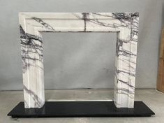 a white marble fireplace surround with black stand