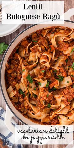 a large pot filled with pasta and meat on top of a wooden table next to utensils