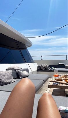 a woman's legs resting on the back of a boat in front of some lounge chairs