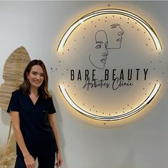 a woman standing in front of a sign that says bare beauty