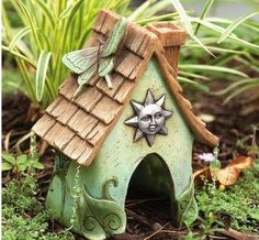 a small green birdhouse with a star on it's roof in the grass