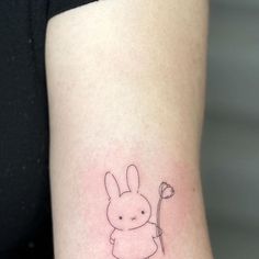 a small rabbit tattoo on the right side of the arm with a flower in it