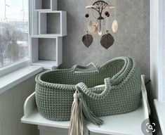 a large green basket sitting on top of a white table next to a window with a chandelier