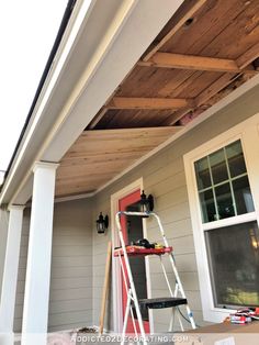 a man is painting the outside of a house with white paint and wood planks