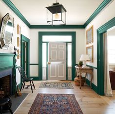 a hallway with green trim and white walls has a rug on the floor next to an open door