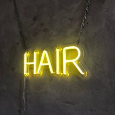 a neon sign that says hair hanging from a chain