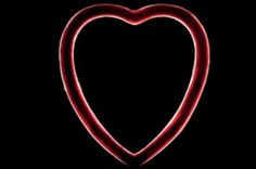 a red neon heart shaped object on a black background