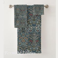 a blue towel hanging on a metal bar in front of a white wall with flowers and leaves