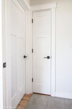 an empty room with two white doors and a rug on the floor