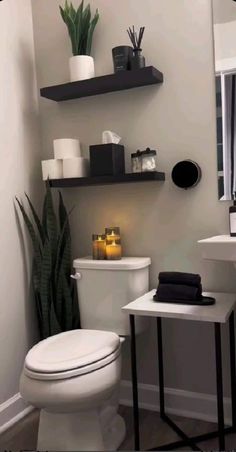 a white toilet sitting in a bathroom next to a sink under a mirror with candles on it