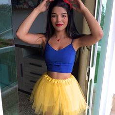 a woman in a blue top and yellow skirt posing for the camera with her hands on her head