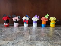 several mickey mouse vases with flowers in them on the floor next to a wall