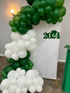 the balloon arch is decorated with green and white balloons