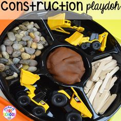 a black tray with construction playdoughs on it and rocks in the background