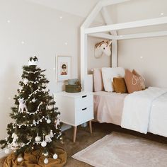 a bedroom decorated for christmas with a bed and small tree in the corner next to it