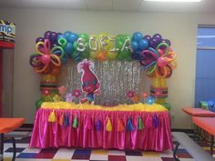 a decorated table with balloons and streamers in the shape of animals, flowers, and letters