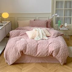 a bed with pink comforter and pillows on it