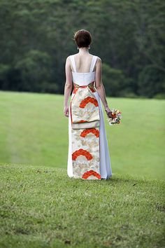 a woman in a long dress standing on top of a lush green field