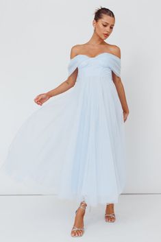 a woman wearing a white dress with an off the shoulder top and tulle skirt