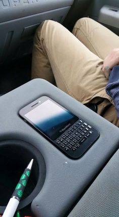 a man sleeping in the back seat of a car next to a cell phone and pen