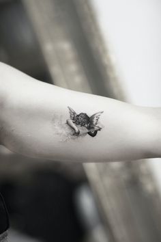 a person with a small owl tattoo on their arm