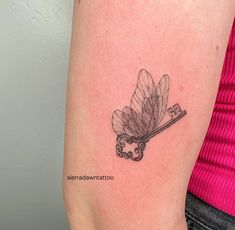 a woman's arm with a key and leaf tattoo on the back of it