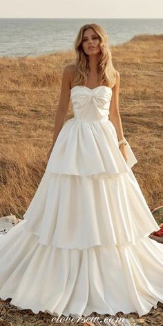 a woman in a wedding dress standing on the beach