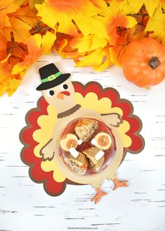 a turkey shaped plate with marshmallows and candy on it next to fall leaves