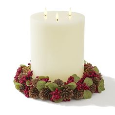 a lit candle surrounded by pine cones and berries