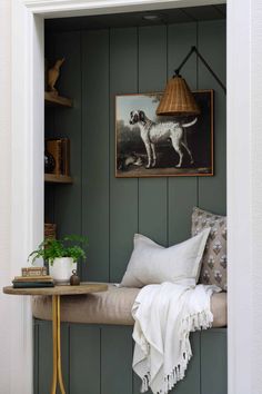 a dog is standing in the corner of a room next to a table with pillows on it