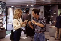 a man standing next to a woman holding a microphone in front of a display case