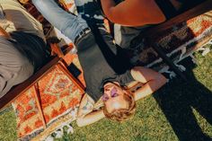 two people laying on the ground in front of a rug