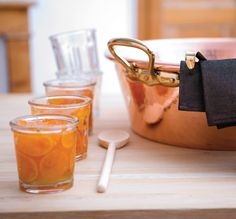 two glasses and a copper pot on a table with utensils next to it