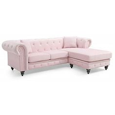 a pink sectional couch sitting on top of a white floor next to a footstool