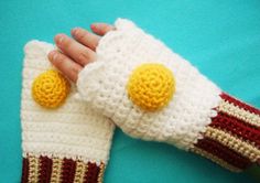 someone is holding their hand in a knitted mitt with two yellow buttons on it