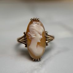 Beautiful vintage handcarved Sardonyx cameo ring set in 10K gold.  The portrait is of a woman looking to the right, with a classic up-do hairstyle. Preloved item, wiggles slightly in the setting. Size (approx.): 5.75 US Stamped 10KT gold Weight: 3.034g **FREE shipping within Canada and USA** If you have any questions or concerns, please do not hesitate to contact us. We will be more than happy to help you and answer any inquiries.  We invite you to check out our shop for more fabulous items! Victorian Gold Cameo Rings, Victorian Cameo Rings For Anniversary, Cameo 14k Gold Rings For Collectors, Antique Cameo Signet Ring For Weddings, Art Deco Cameo Ring For Collectors, Gold Cameo Signet Ring Collectible, Cameo 14k Gold Rings For Anniversary, Antique Carved Rings For Anniversary, Gold Oval Cameo Rings