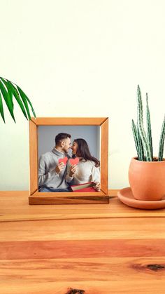 a potted plant sitting next to a wooden table with a photo frame on it