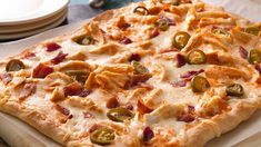 a pizza sitting on top of a cutting board covered in cheese and olive toppings