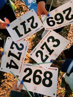 four people holding up numbered signs with numbers on them in front of some grass and leaves