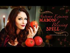 a woman holding an apple in front of her face and surrounded by apples on a table