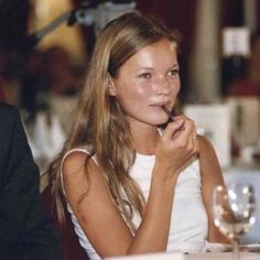 a woman sitting at a table with a pen in her mouth