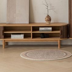 a wooden entertainment center sitting on top of a hard wood floor next to a vase