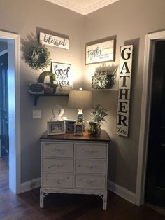 a white dresser sitting in the corner of a room with pictures hanging on the wall