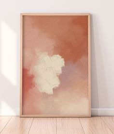 an abstract painting in a wooden frame on the floor next to a white wall and hardwood floor